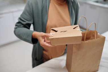 Hands of woman taking boxes with food out of paper package