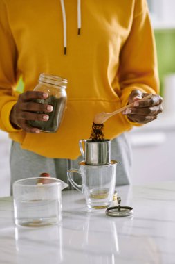 Cropped image of young woman putting ground coffee in phin filter to make Vietnamese style coffee