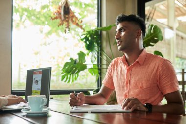 Serious entrepreneur talking to colleague when they are working in cafe