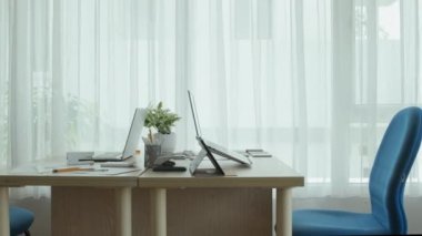 Çalışma odasında üzerinde dizüstü bilgisayarlar olan ofis masalarının görüntülerini izliyorum.