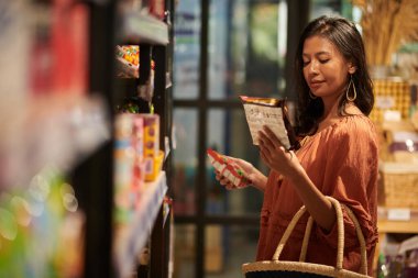 Smiling woman buying packages of ramen in supermarket