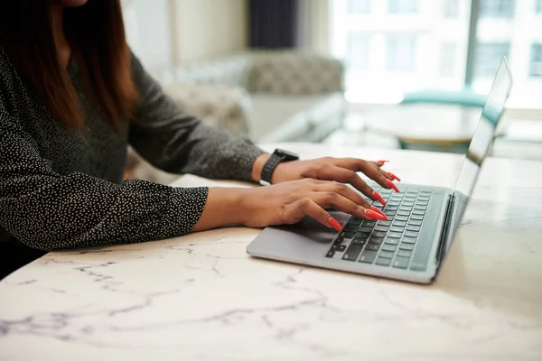 Businesswoman with long red nails working on laptop at desk
