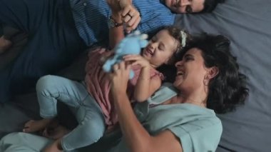 Kafkasyalı mutlu lezbiyen çiftin ve sevgili küçük kızlarının evde yatakta birlikte oynamalarının en iyi görüntüsü.