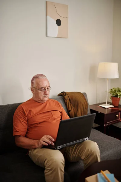 Ανώτερος Άνθρωπος Κάθεται Στον Καναπέ Και Εργάζεται Φορητό Υπολογιστή — Φωτογραφία Αρχείου