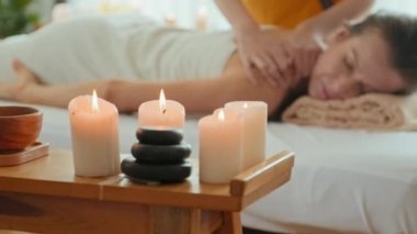 Young natural Caucasian woman relaxing with her eyes closed on comfortable massage bed while receiving back massage in luxury spa resort