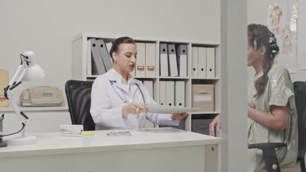 診療所での診察中に妊娠中の女性に医療契約をする女性医師 — ストック動画
