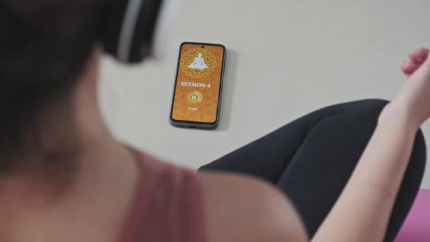 Shoulder Shot Woman Headphones Turning Meditation App Smartphone While Sitting — Stock videók