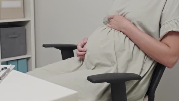 診察中に医務室に座って医師として腹を撫でている妊婦の集団撮影 — ストック動画