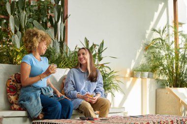 Female friends having drinks and discussing news in cafe
