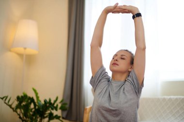 Woman raising arms above head and doing breathing exercise