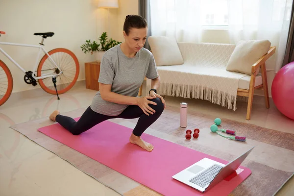 Woman following online fitness instrustor when doing deep lunges at home