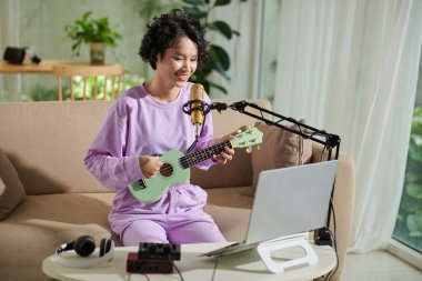 Neşeli genç kız gitar çalıp şarkı söylemekten zevk alıyor.