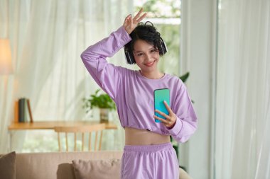 Smiling girl making peace gesture when video calling friends