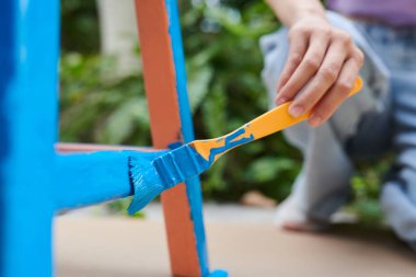 Teenage girl enjoying restore old wooden furniture and painting blue