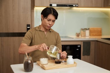 Young man pouring hot water in phin filter when making morning coffee