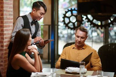 Man telling restaurant waiter what he wants to order for dinner