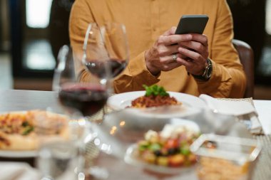Man texting girlfriend when eating dinner in restaurant