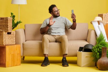 Smiling man sitting on couch and video calling friend or family member