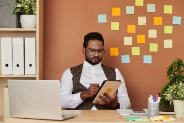 Frowning serious man writing document on digital tablet when working at office desk