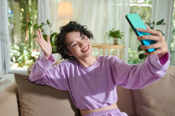 Portrait of smiling teenage girl taking selfie or filming video on smartphone