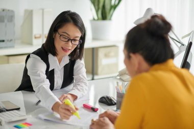 Insurance agent helping senior woman to understand details in agreement