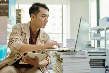 College student watching webinar on laptop and writing down important thoughts