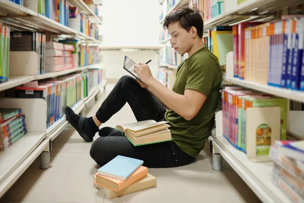 Estudiante Universitario Inteligente Sentado Suelo Biblioteca Escribiendo Ensayo Tableta —  Fotos de Stock