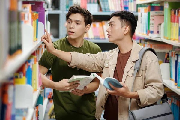 Teenage Boy Helping Classmate Find Book Library — Stok fotoğraf