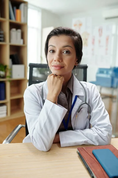 Portret Uśmiechniętej Kobiety Praktykującej Medycynę Ogólną Siedzącej Przy Biurku Patrzącej — Zdjęcie stockowe