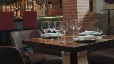Restoranda konuklar için şarap kadehleri ve tabaklar hazırlanmış seçmeli bir masa fotoğrafı.