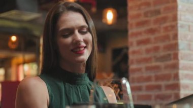 Genç ve güzel bir kadın restoranda yemek yerken menü okuyup yemek seçiyor.