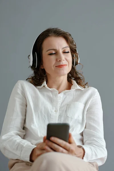 幸せな成熟した女性閉じ目とき楽しい音楽からプレイリスト彼女のスマートフォン — ストック写真