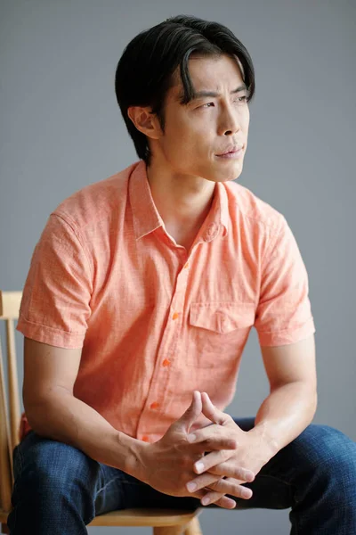 Pensativo Joven Asiático Hombre Sentado Silla Mirando Hacia Otro Lado — Foto de Stock