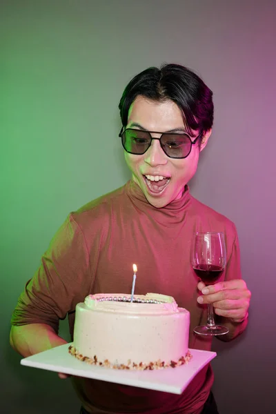 Emocjonalnie Podekscytowany Młody Azjata Szklanką Wina Patrząc Tort Urodzinowy — Zdjęcie stockowe