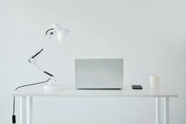 Minimalistyczne Wnętrze Białe Biurko Laptopem Lampą Smartfonem Filiżanką Kawy — Zdjęcie stockowe