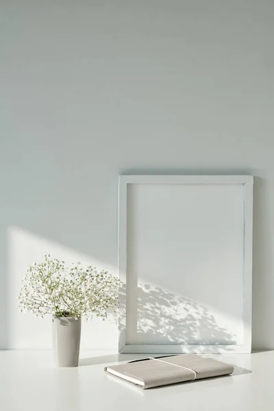 机の上に花やプランナーと花瓶の横に空の画像フレーム — ストック写真