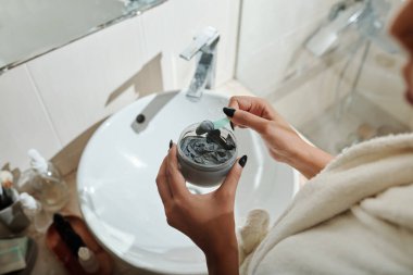 Kadının elleri plastik kavanozdan nemlendirici yüz maskesi alıyor.