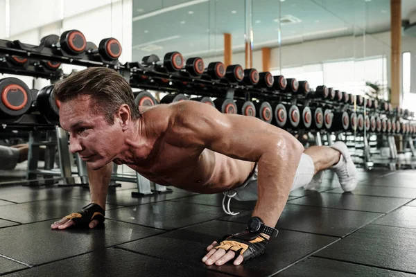 床の上でプッシュアップを行う強い筋肉の男 — ストック写真
