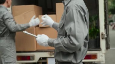 Meslektaşı kamyonu boşaltırken servis elemanının kutuları sayıp not aldığı görüntüler.