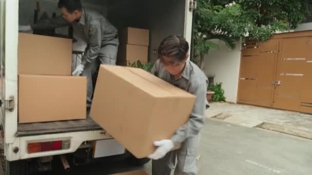两名身穿制服和手套的亚洲流动服务人员从卡车上卸下纸板箱 然后把纸板箱堆在外面的街上 — 图库视频影像