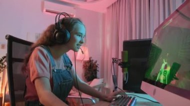Evinde geç saatlere kadar oynarken bilgisayarda FPS oyunu kazanan neşeli beyaz kız.