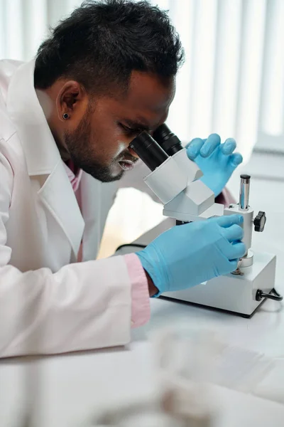 Vista Lateral Joven Científico Afroamericano Mirando Microscopio Mientras Está Sentado —  Fotos de Stock