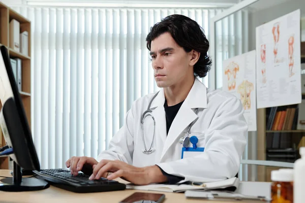 Young Serious Doctor Lab Coat Typing Keyboard While Sitting Workplace — Stock Photo, Image