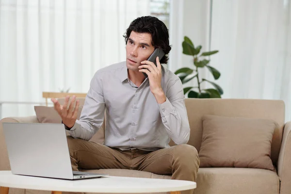 Jovem Empresário Sério Explicando Algo Telefone Celular Enquanto Senta Sofá — Fotografia de Stock