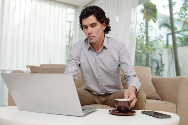 사업가 직장에서 컴퓨터 소파에 커피를 마시고 온라인 비디오를 있습니다 — 스톡 사진
