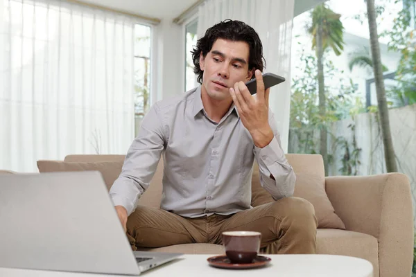 Genç Ciddi Bir Erkek Çalışan Akıllı Telefonuyla Konuşuyor Dizüstü Bilgisayarın — Stok fotoğraf