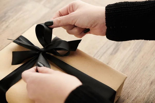 Руки Женщины Открывают Подарок День Рождения Украшенный Черной Лентой — стоковое фото