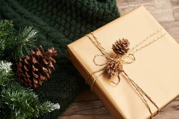礼物用金纸包裹 在桌上的绿色针织毛衣旁边装饰着松果 — 图库照片