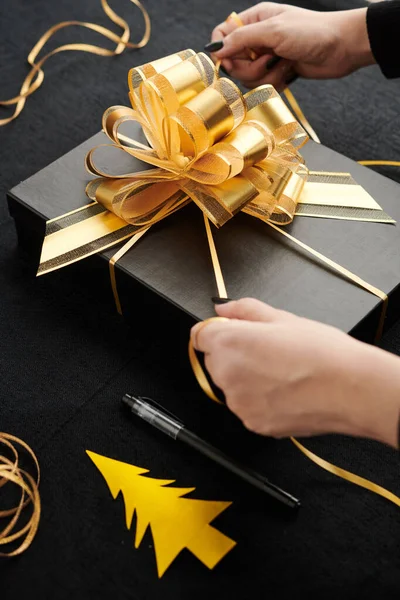 Frauenhände Binden Große Goldene Schleife Auf Schachtel Mit Weihnachtsgeschenk — Stockfoto