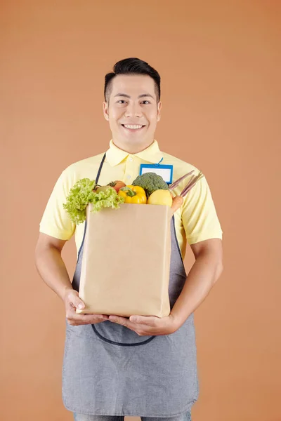 Uśmiechnięty Azjatycki Pracownik Supermarketu Trzymający Papierową Torbę Pełną Świeżych Artykułów — Zdjęcie stockowe